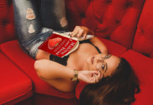 Sex coach reading a book on a red sofa