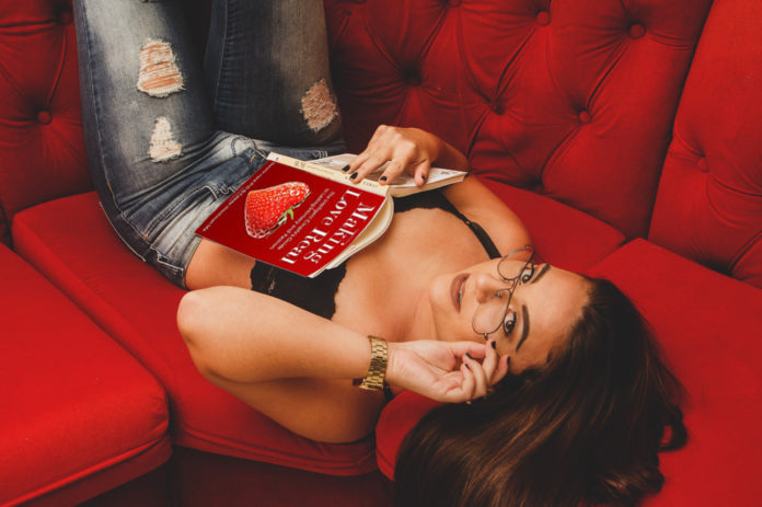 Sex coach reading a book on a red sofa