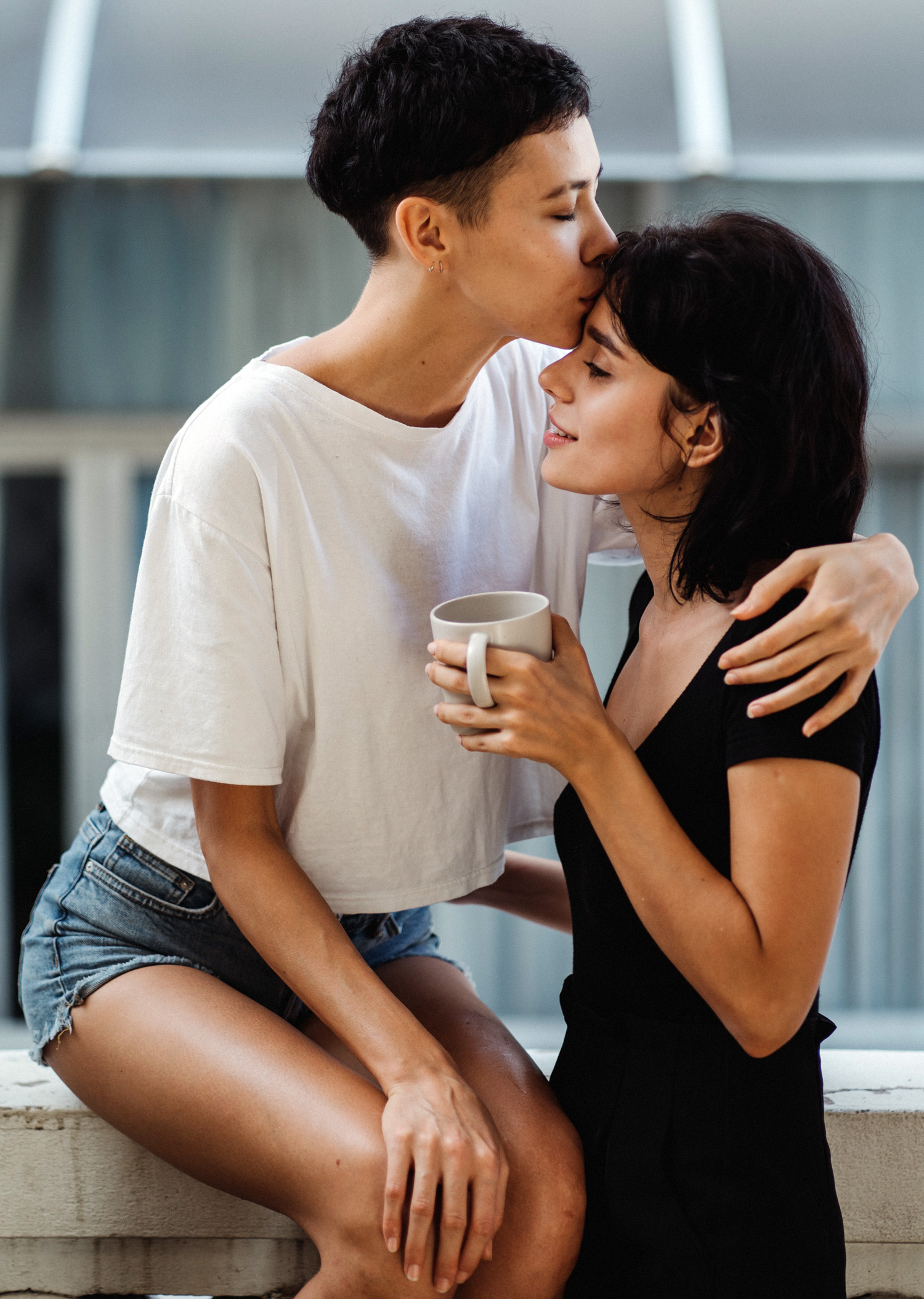 Greysexual woman kissing another's forehead