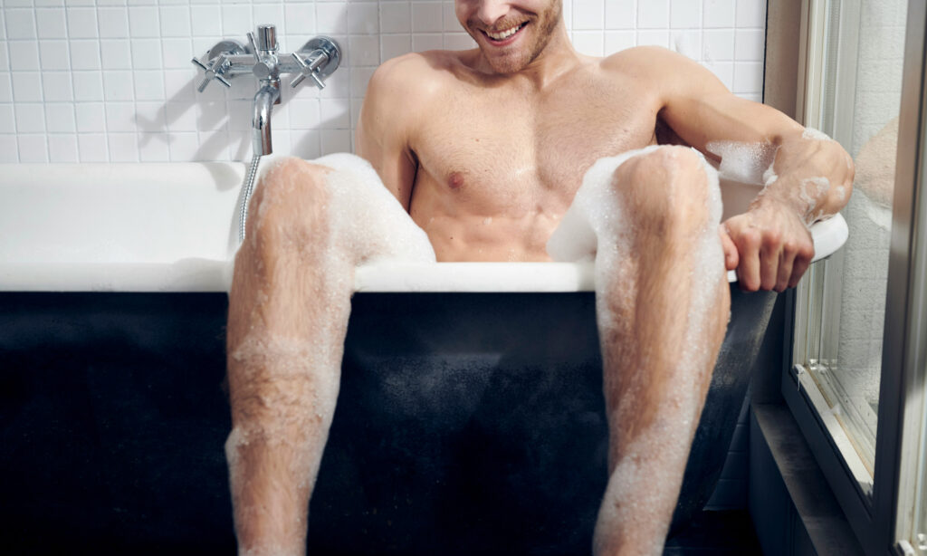 Smiling man in bath tub, masturbating